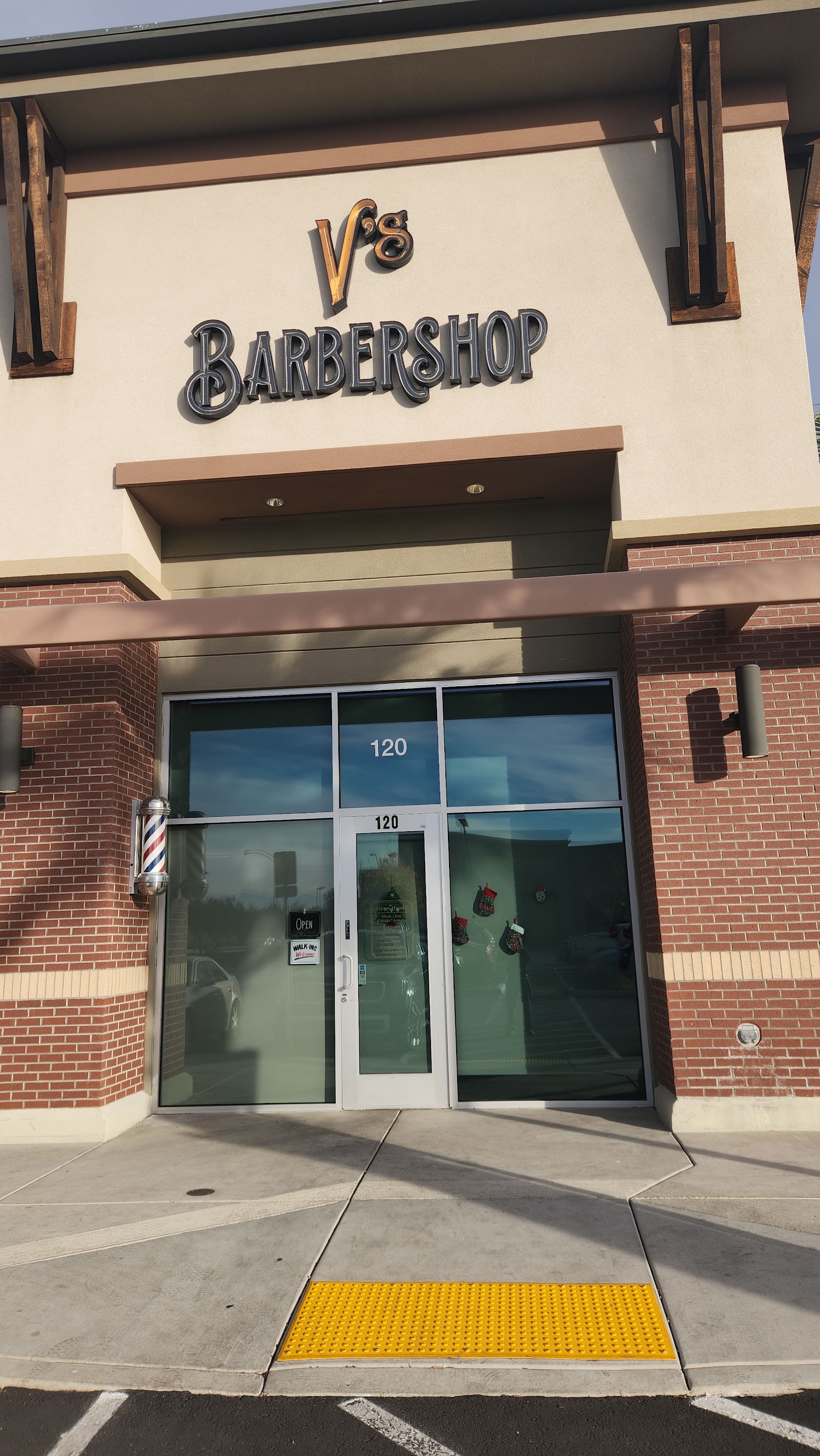 Exterior of V's Barbershop with signage, a barber pole and the suite 120 entrance